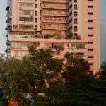 Tall apartment building with balconies and trees.